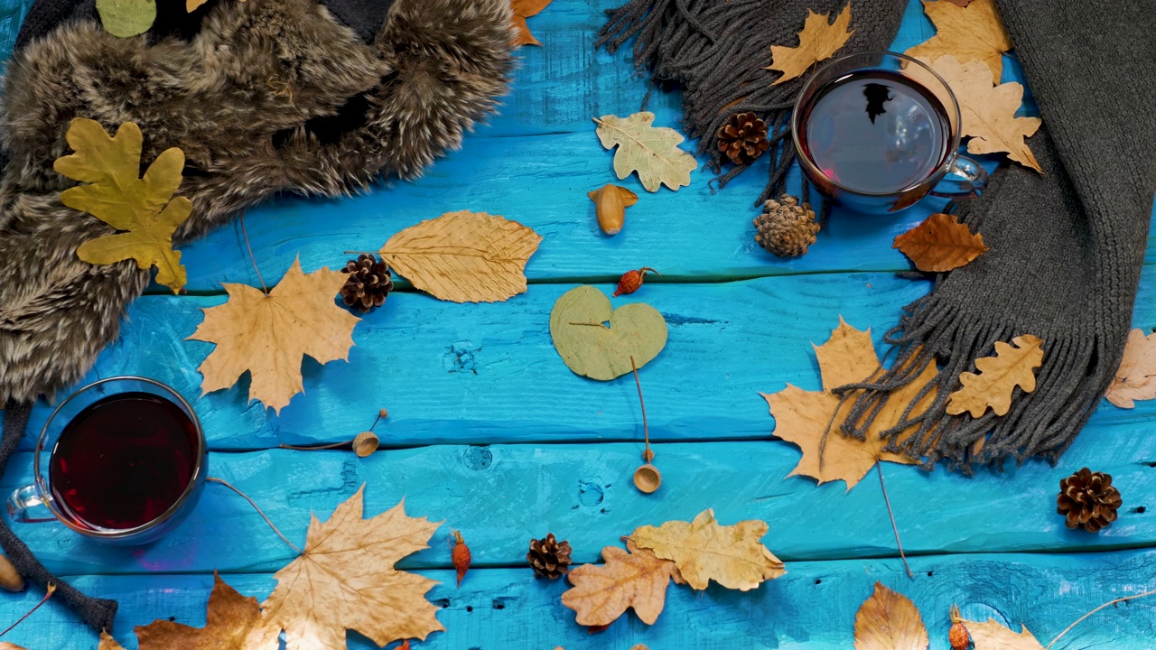 黄色的树叶落在茶几上，秋天的背景是茶，树叶从古色古香的蓝色桌子上的一棵树上落下。舒适的秋天背景与复古的桌子。桌上放着红莓茶视频下载