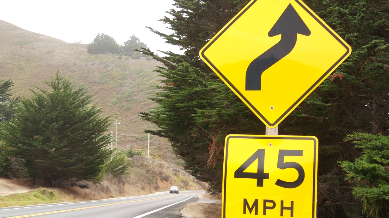 黄色限速标志，弯道、转弯或蜿蜒的道路。加利福尼亚州，大苏尔，美国视频下载