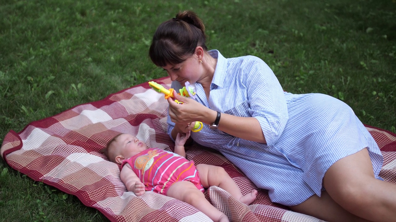 年轻的母亲在公园里和婴儿玩玩具视频下载
