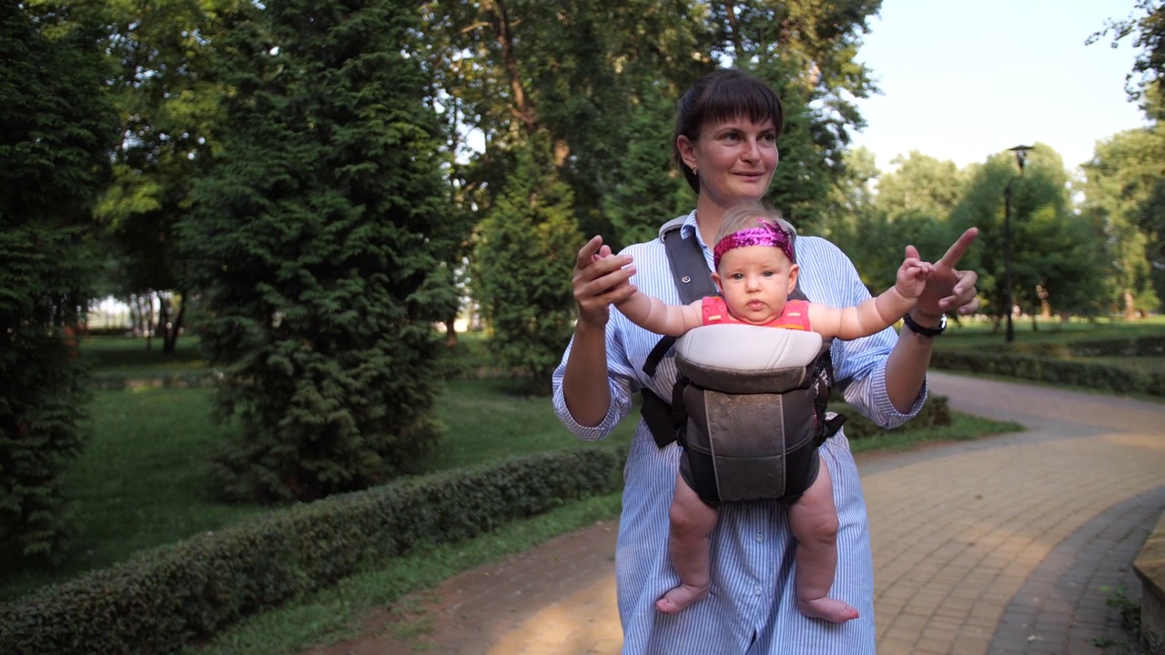 妈妈和一个小女孩在公园里散步。妇女抱着婴儿在克古鲁。4K慢墨视频下载