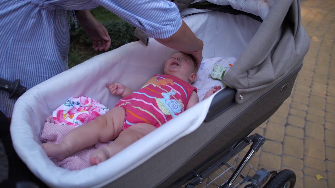年轻的母亲在婴儿车里安慰哭泣的婴儿视频下载