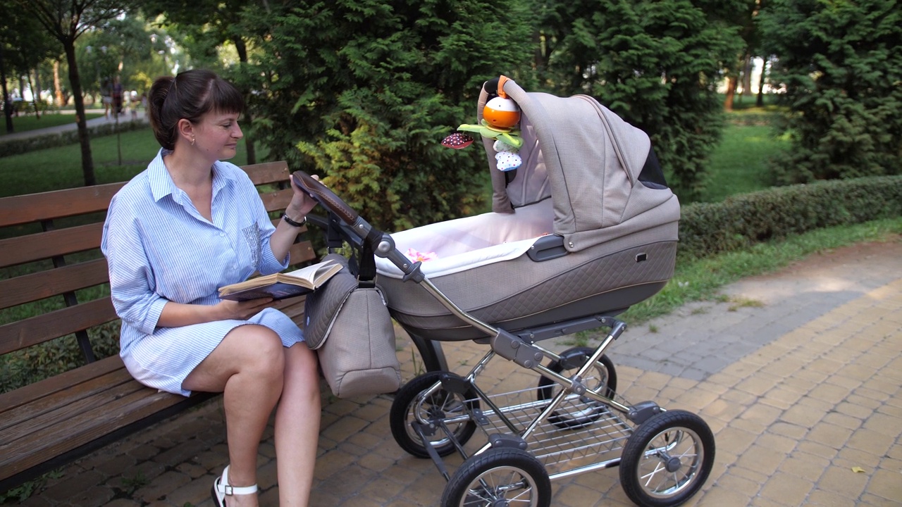 妈妈推着婴儿车看书。视频下载