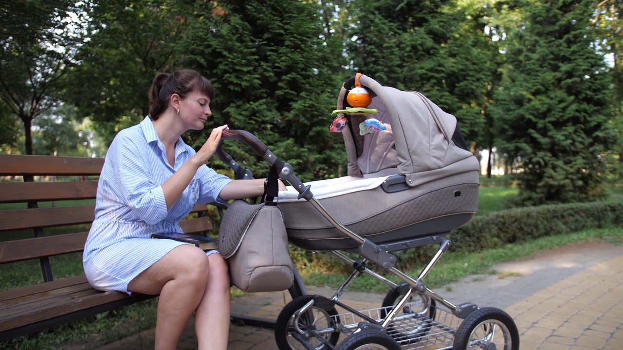 放大一个坐在公园里推着婴儿车的女人视频下载