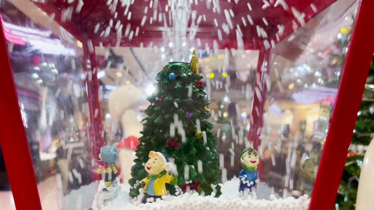 戴着鲜艳帽子的圣诞娃娃在一棵雪树和圣诞和新年装饰品前排成一排。视频下载