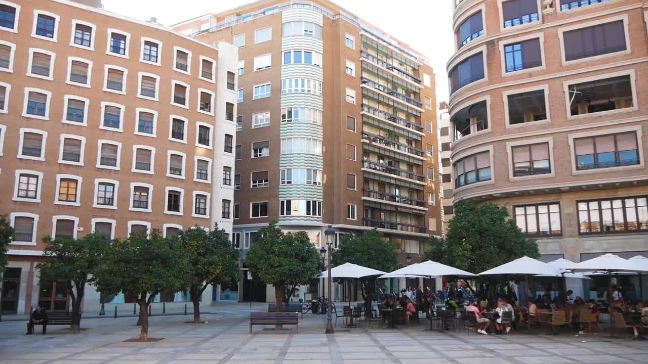 高楼林立的城市广场和人们坐着撑伞的咖啡馆视频下载