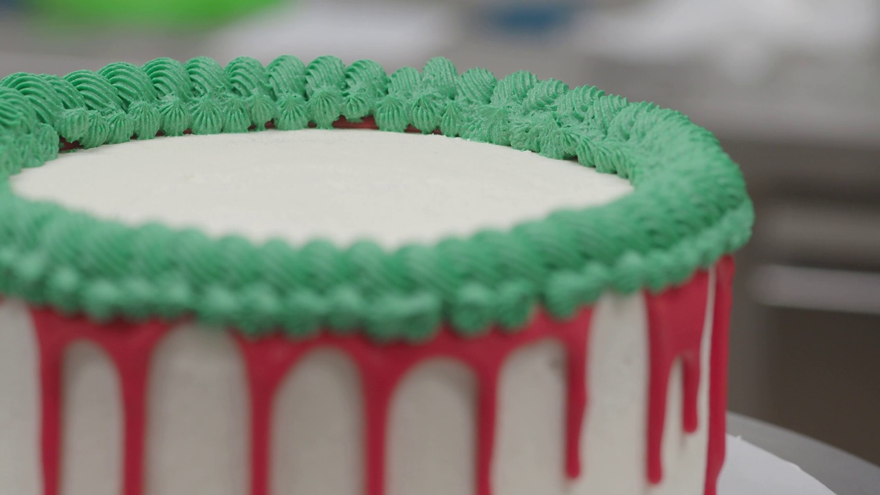 手工糕点厨师设计师顶一个磨砂白色蛋糕挤压红色绿色滴填充袋4k视频视频下载