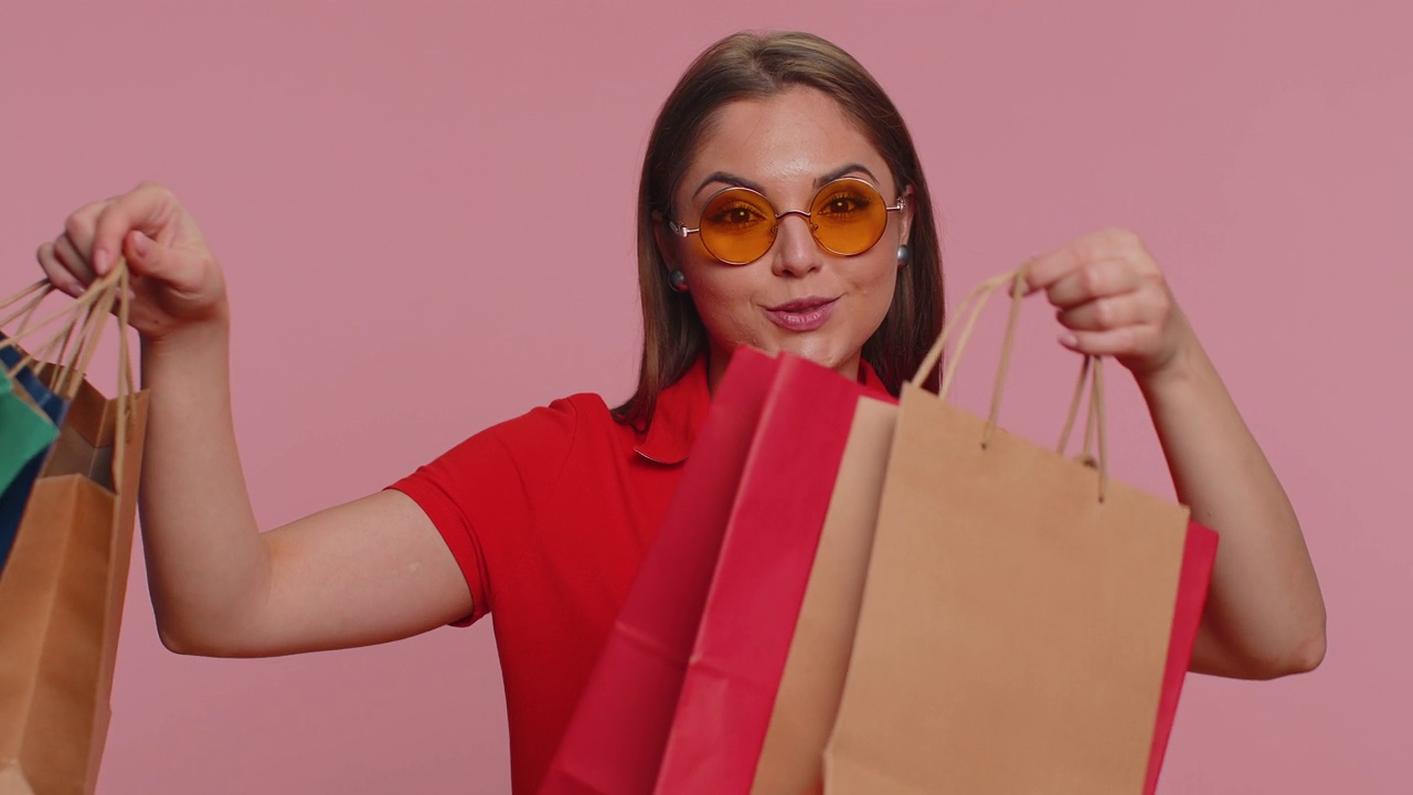 快乐的女游客展示购物袋，宣传假期折扣，惊叹于低廉的价格视频素材