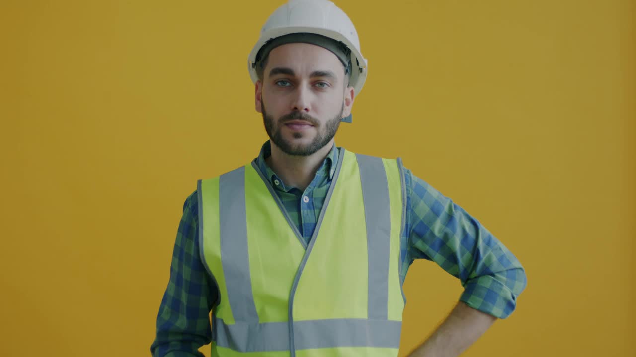 黄色背景上欢快的建筑经理拿着房子钥匙微笑的慢镜头视频素材
