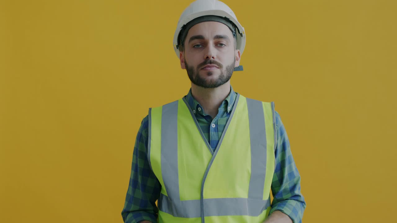 年轻男子建筑工人的肖像在黄色背景上玩锤子视频素材