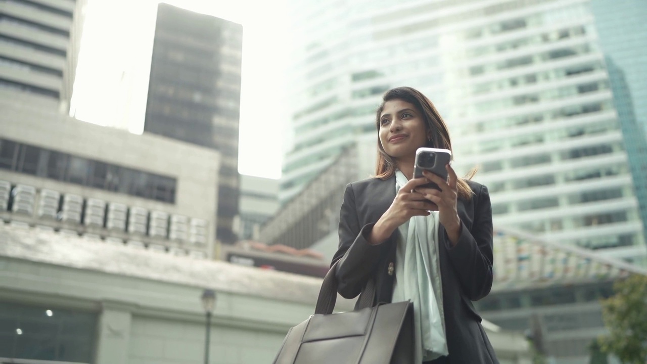 自信的年轻女商人与智能手机站在现代建筑视频下载