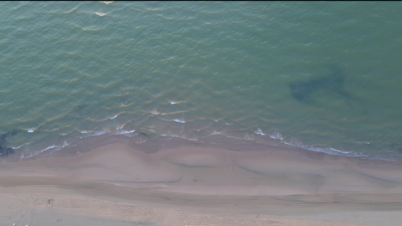 海岸边柔软的沙滩和蓝色的海水的鸟瞰图——慢动作视频素材