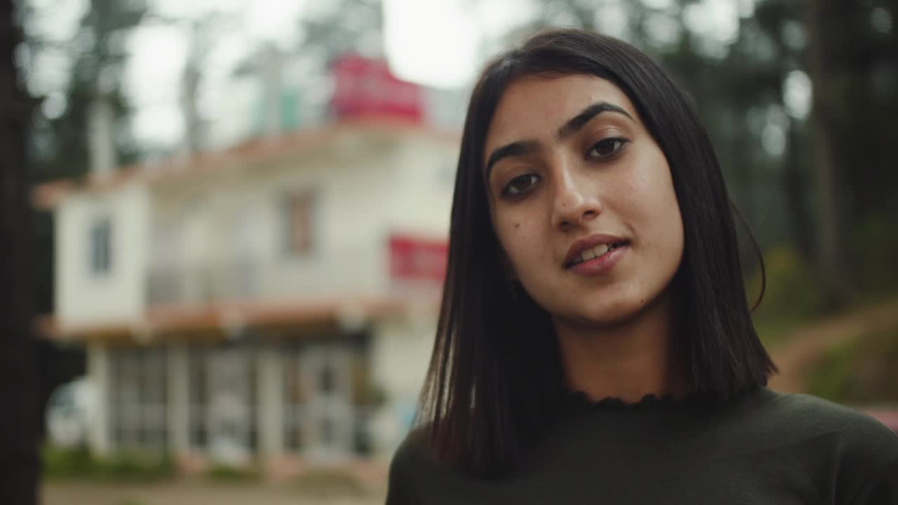 一个南亚女孩带着面具微笑的慢镜头，背景模糊视频下载
