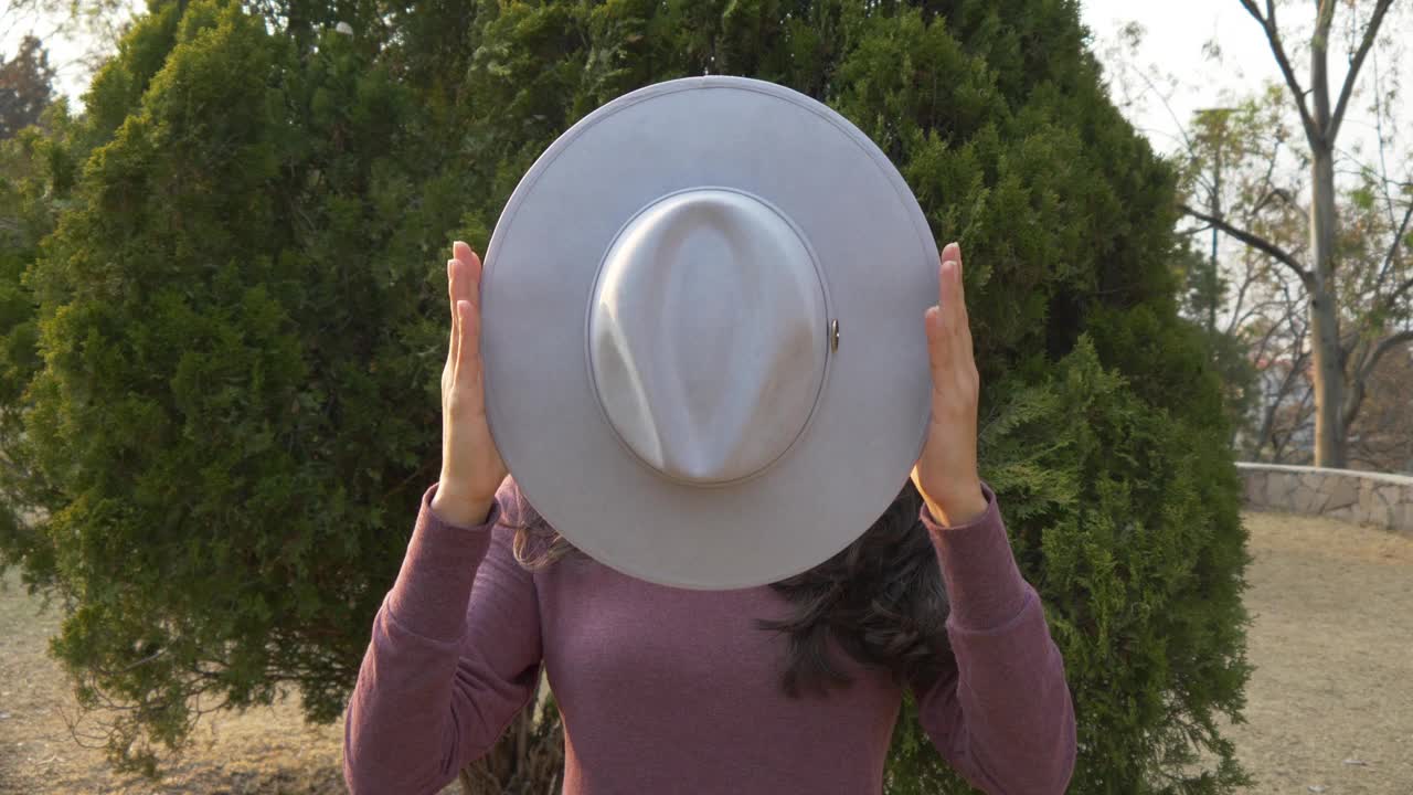 一个西班牙女孩戴着帽子，躲在公园里的漂亮照片视频下载