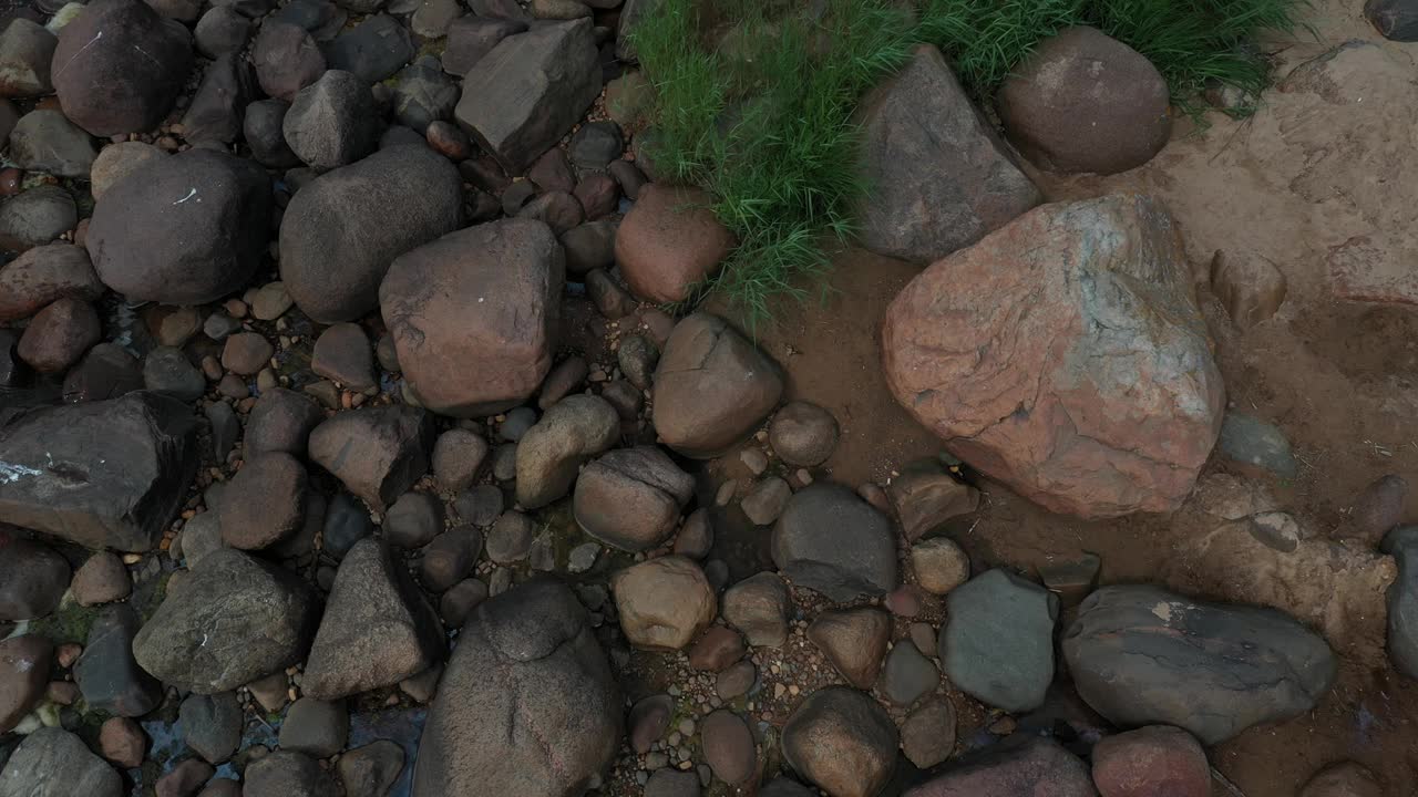 海岸的石头，鹅卵石和波浪的海水在4K的俯视图视频素材