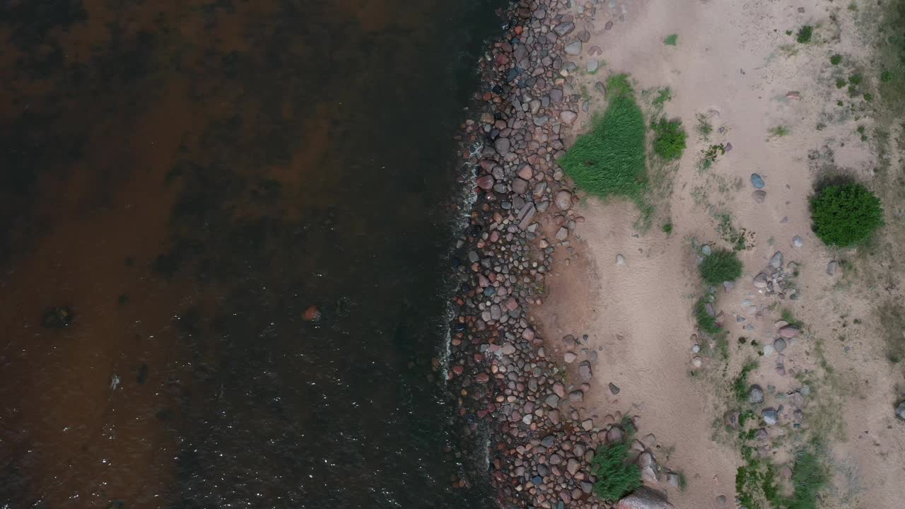 海岸鸟瞰图，棕色的沙子，石头和鹅卵石在4K视频素材