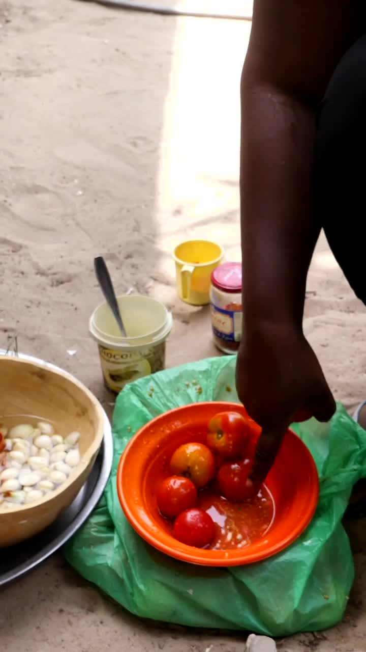 垂直视频的中等镜头的黑人妇女切番茄用刀放在砂浆视频下载