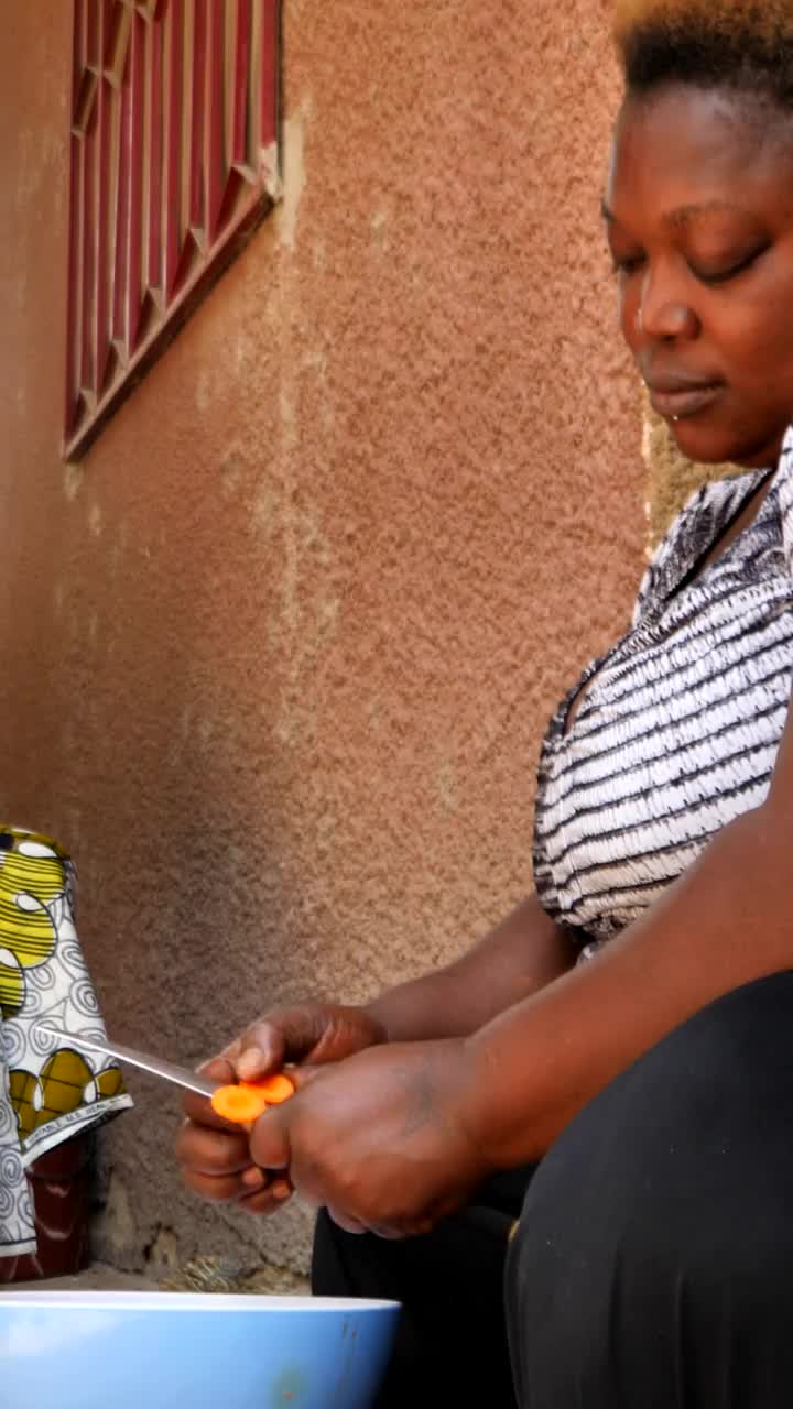 垂直视频宽镜头的黑人妇女切胡萝卜切片，而另一个坐着视频下载