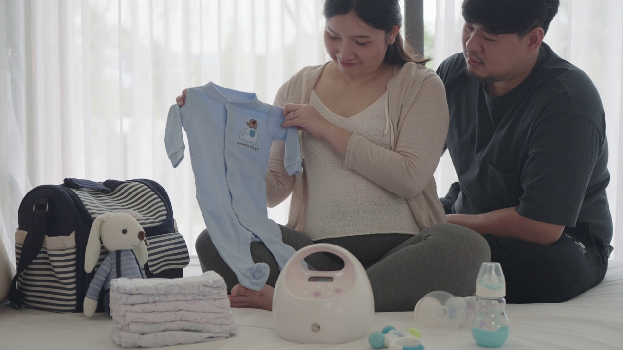 亚洲孕妇和她的丈夫在家里的卧室准备婴儿监视器器具，容器准备怀孕概念。视频下载