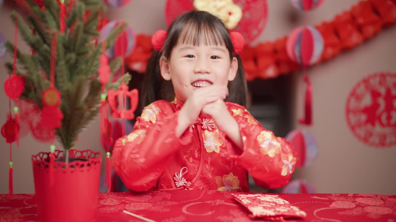 身着传统服饰的小女孩开着红包庆祝春节视频下载