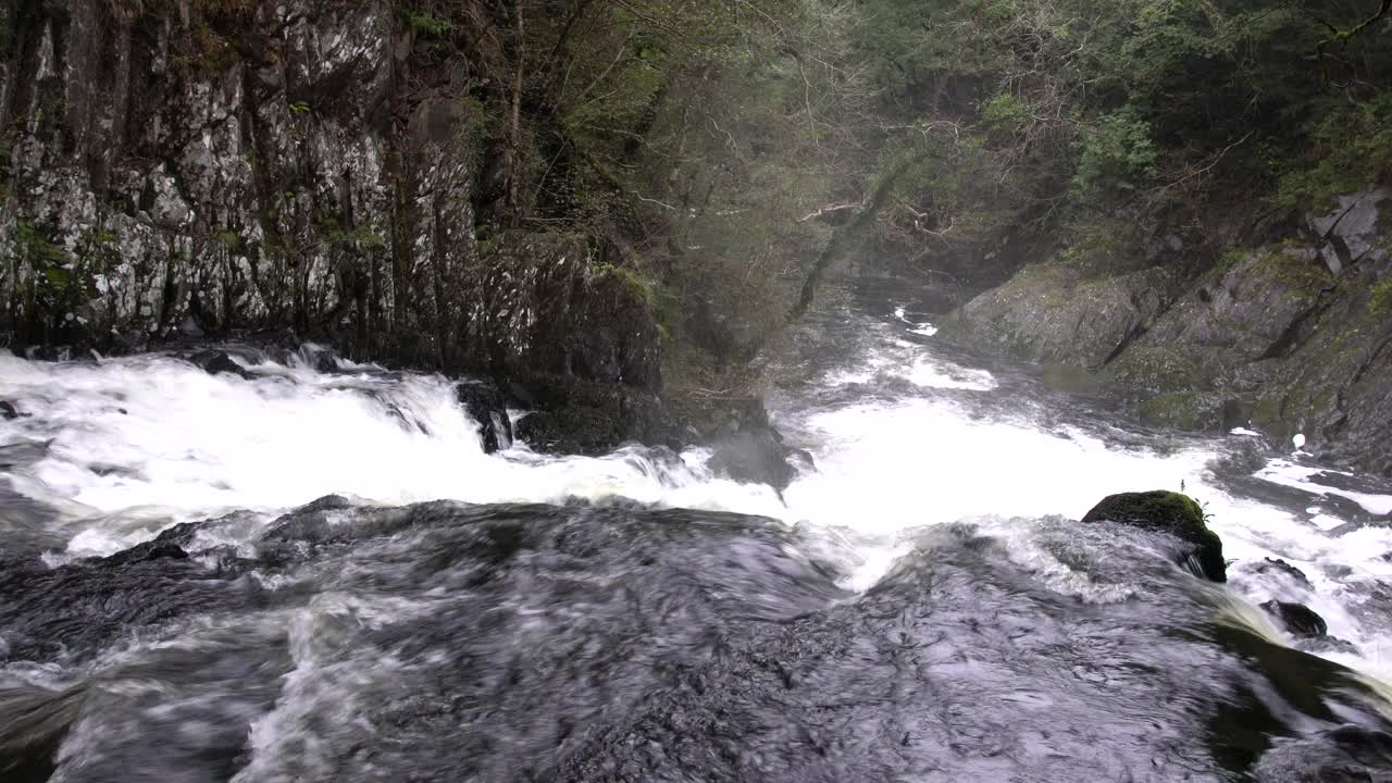 美丽的镜头，飞溅和泡沫的水瀑布和沿着苔藓岩石流动视频素材