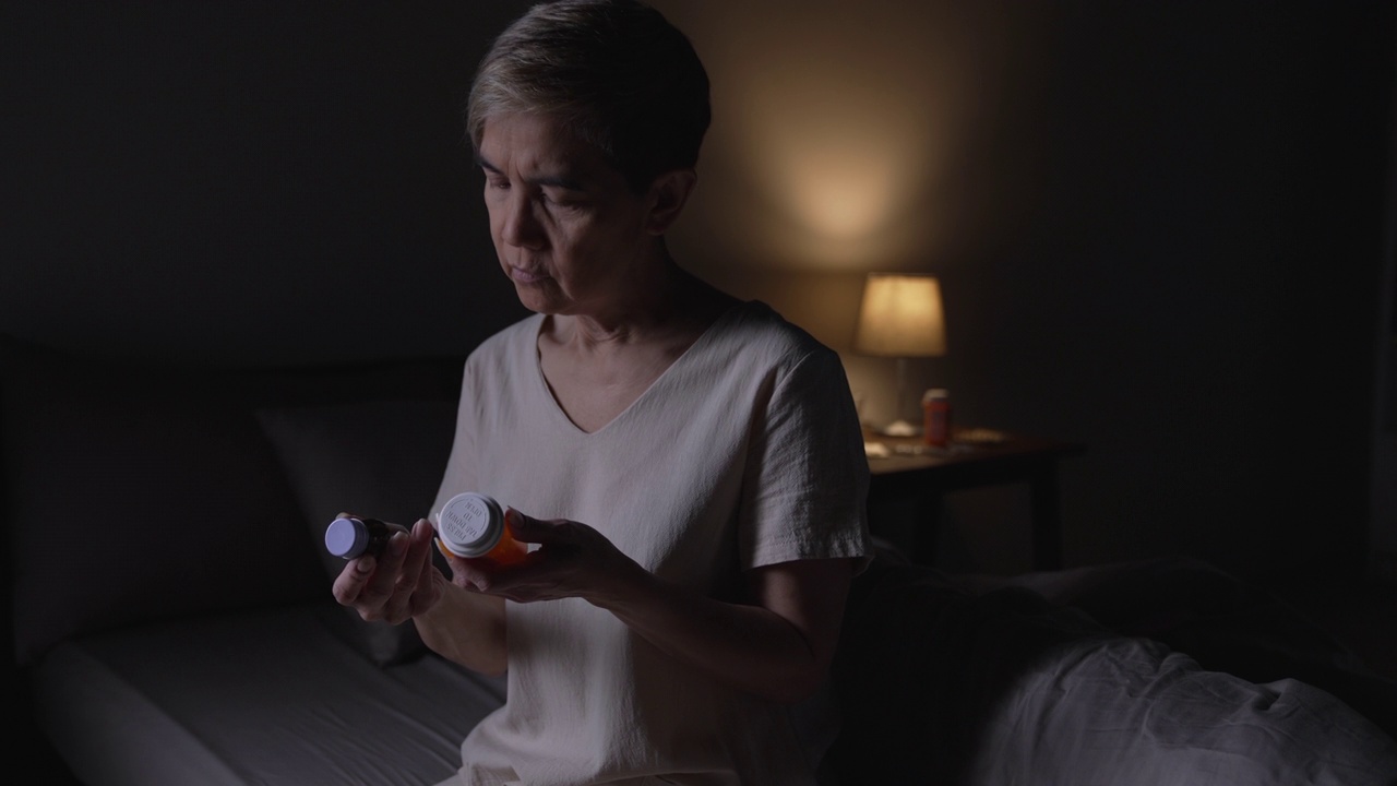 老年亚洲妇女因失眠而无法入睡。高级亚洲妇女服用安眠药。视频素材