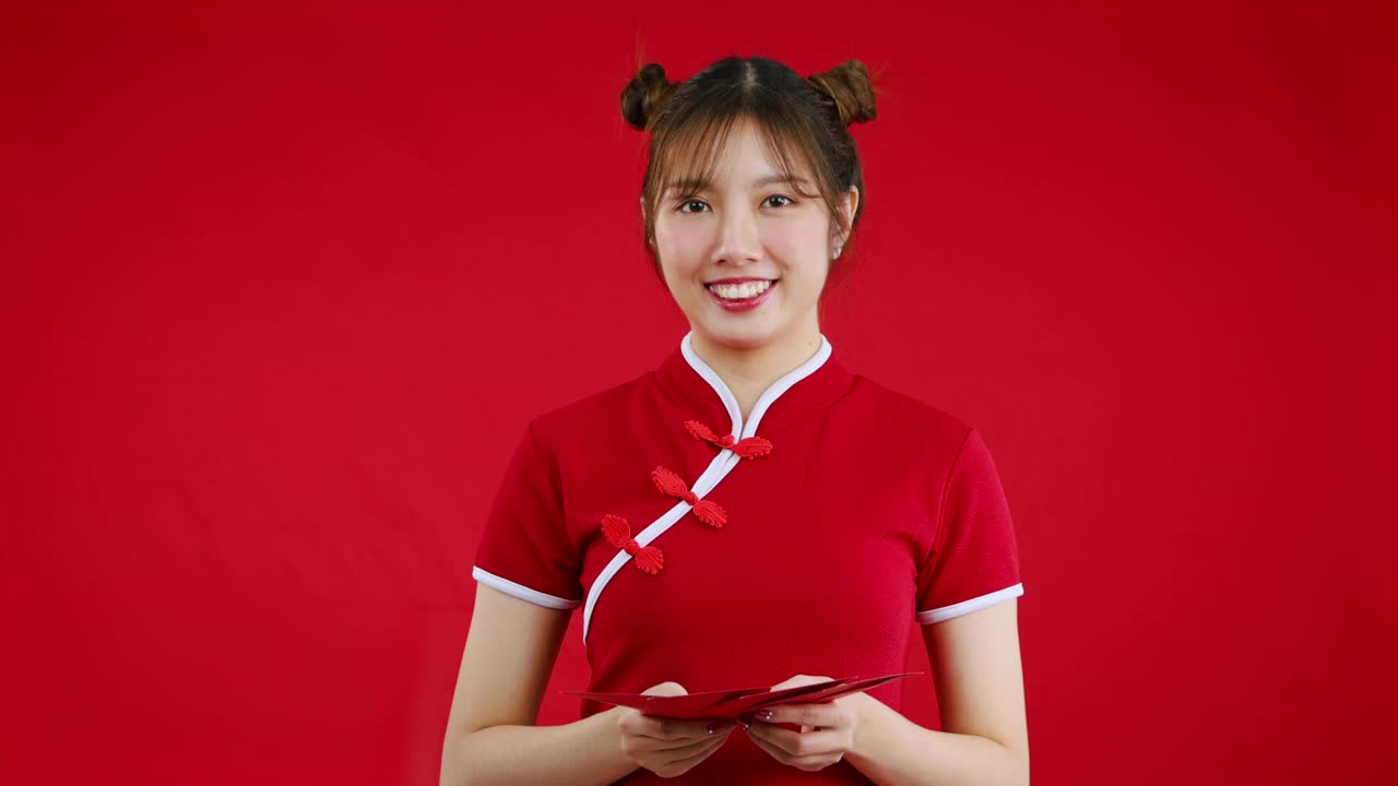 漂亮的亚洲女人拿着红色背景的红包庆祝中国新年。4K视频片段视频下载