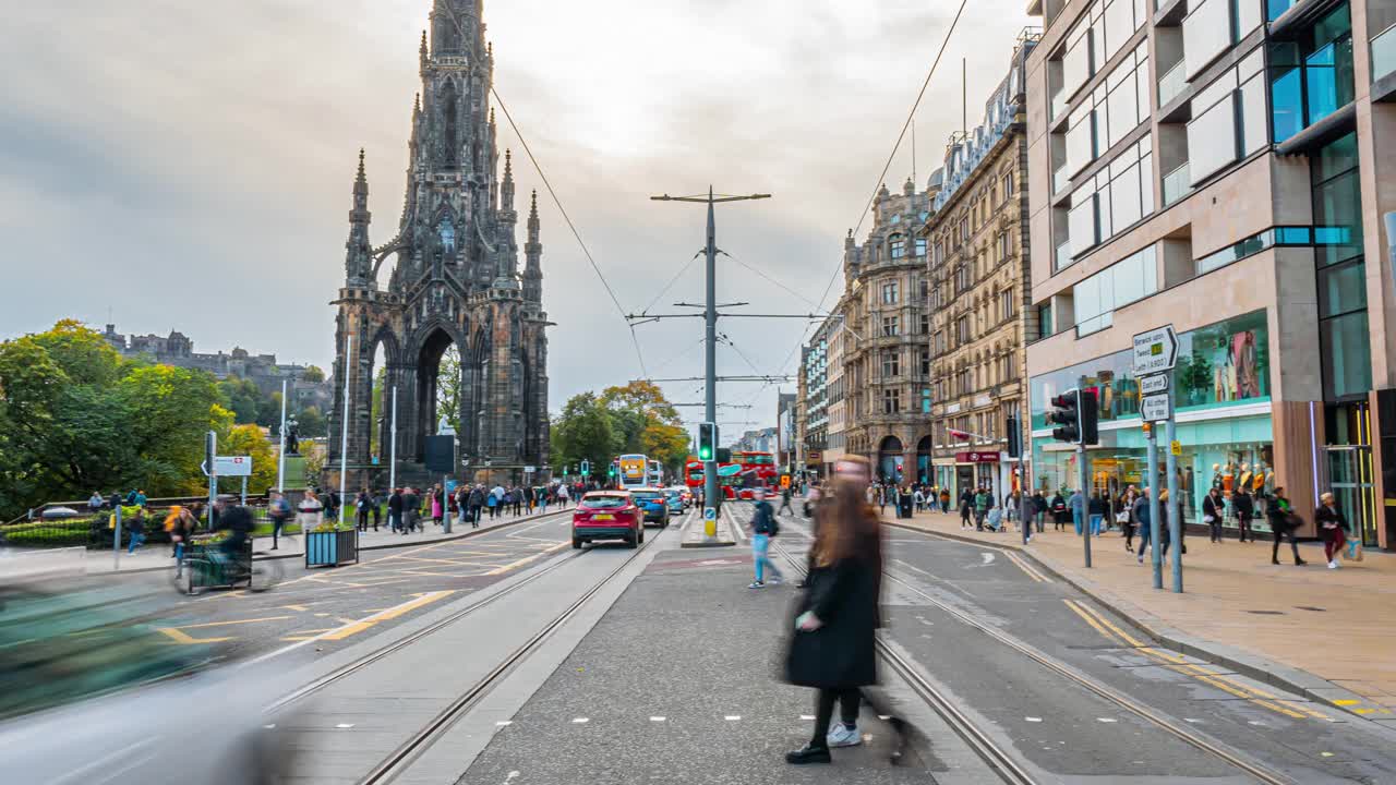 在英国苏格兰爱丁堡的爱丁堡韦弗利火车站附近王子街的斯科特纪念碑周围，人群行人和游客步行和穿越的时间推移视频素材