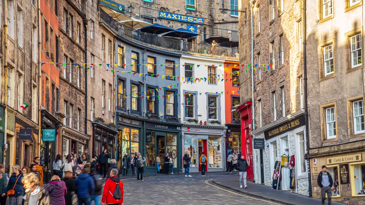 英国苏格兰爱丁堡老城区维多利亚街周围的人群行人和游客步行和观光彩色商店的时间推移视频下载