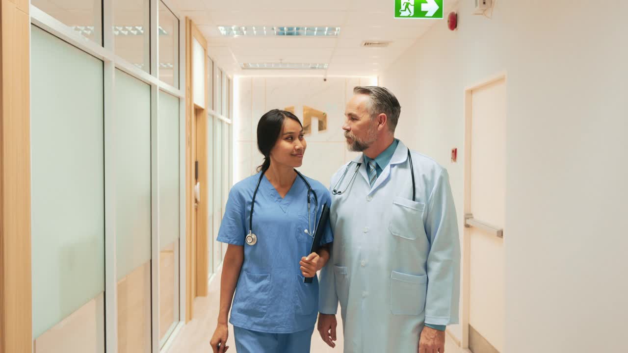 在医院走廊的镜头前，多种族医生和护士站在一起，双臂交叉摆出姿势。视频素材