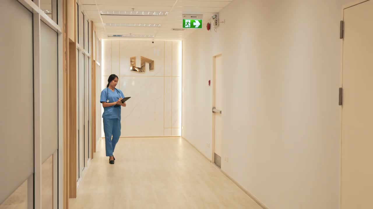 在走廊里，年轻的亚裔护士正在向中年白人医生打招呼视频素材
