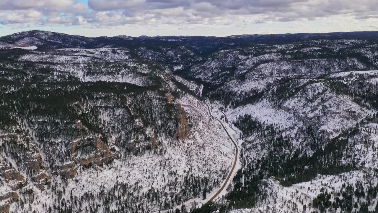 冬天，在大雪纷飞的山谷中飞过蜿蜒的公路视频素材