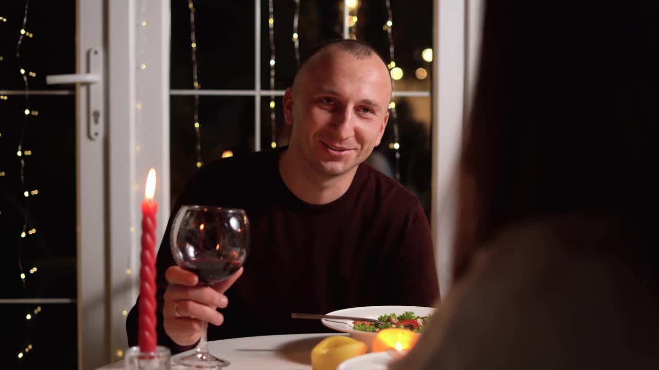 相爱的情侣在餐厅共进晚餐，喝着红酒，快乐的男人给心爱的女人送礼物，庆祝情人节视频下载
