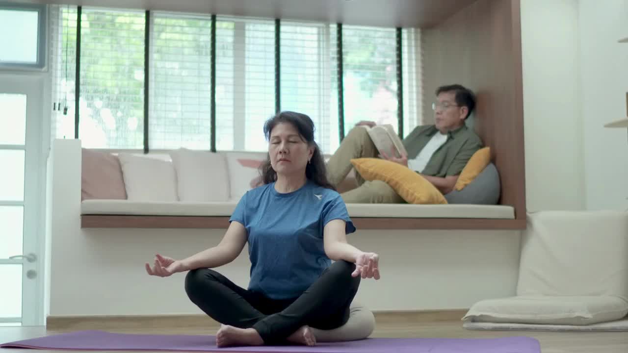 亚洲老年夫妇在周末做瑜伽和看书视频素材