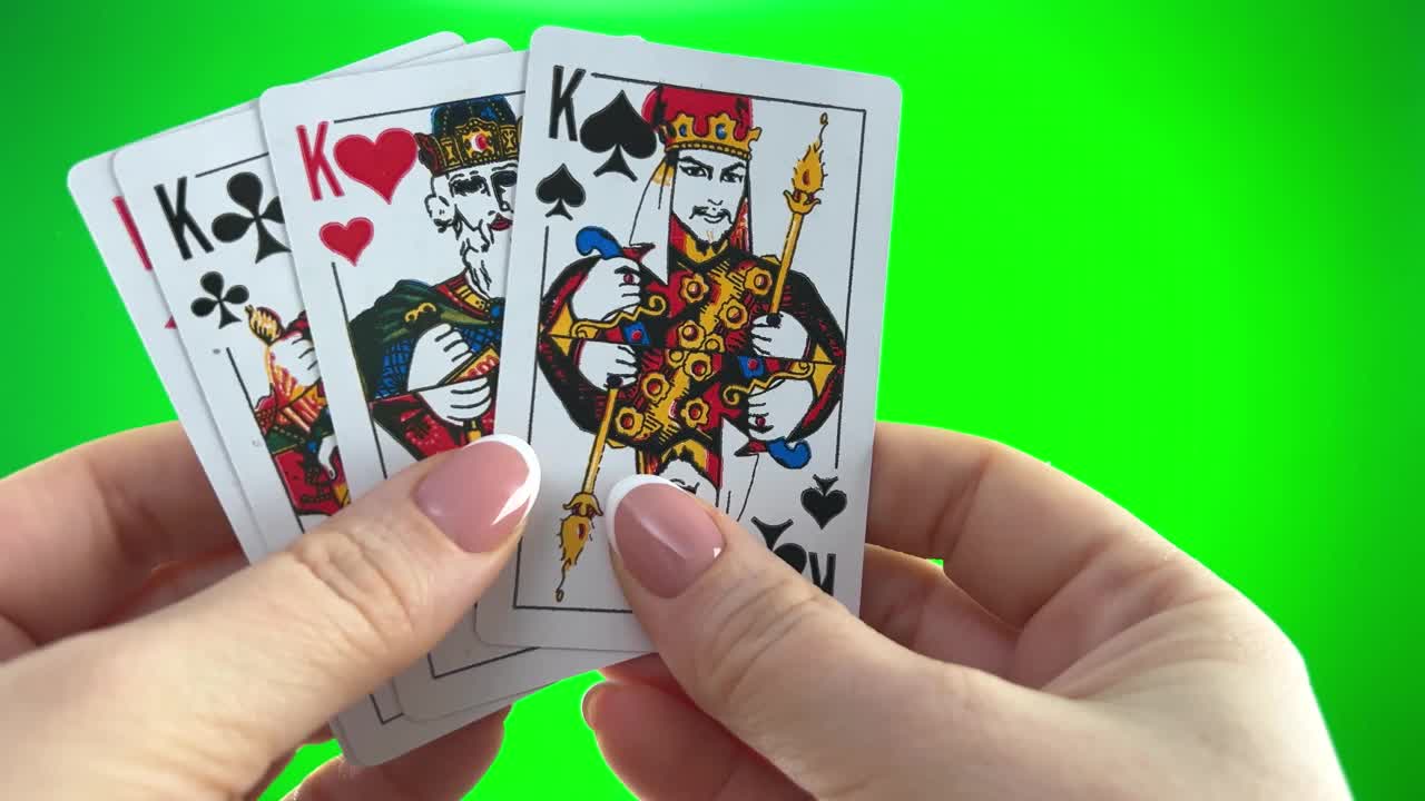 女性手，法式美甲。女人整理卡片，检查它们折叠并像扇子一样展开四张相同花色的牌，手拿四张王牌，在绿色背景上特写视频下载