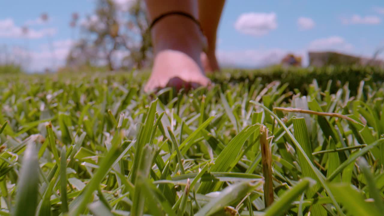近距离，景深:年轻的赤脚女子在绿色的花园草地上走向摄像机视频素材