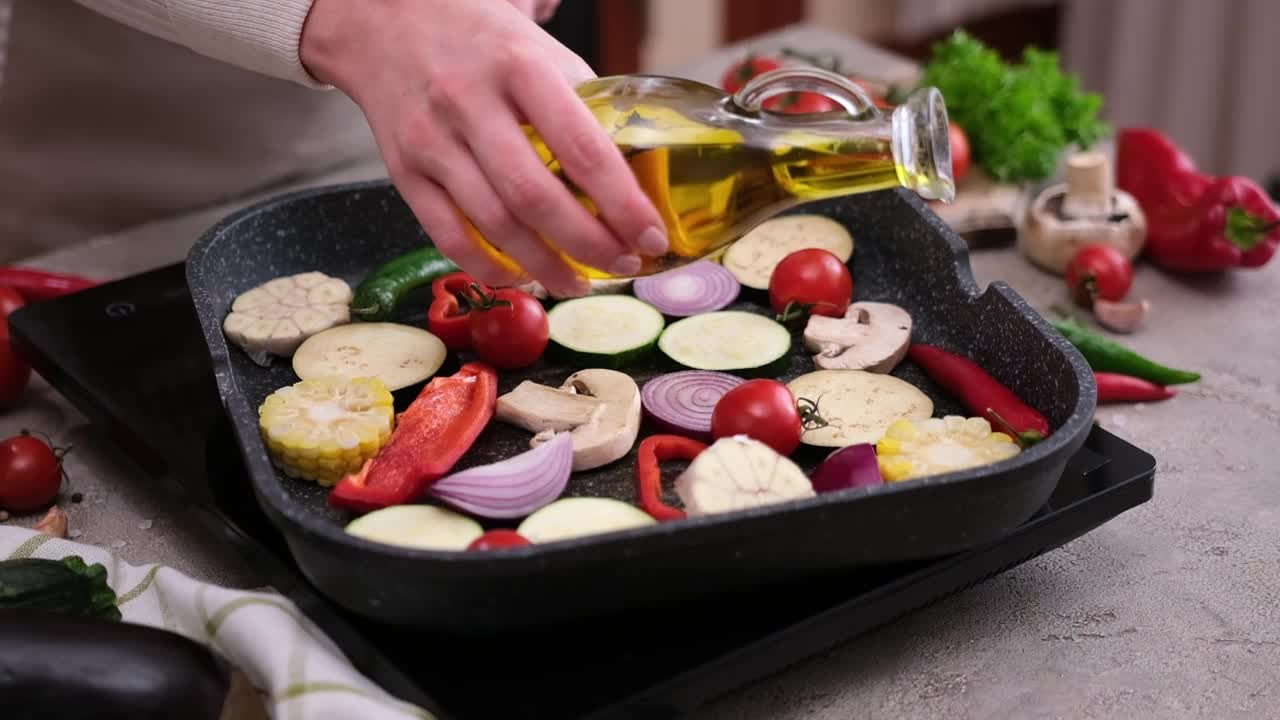 一名妇女将烹饪橄榄油倒在烧烤煎锅里的切片蔬菜上视频下载