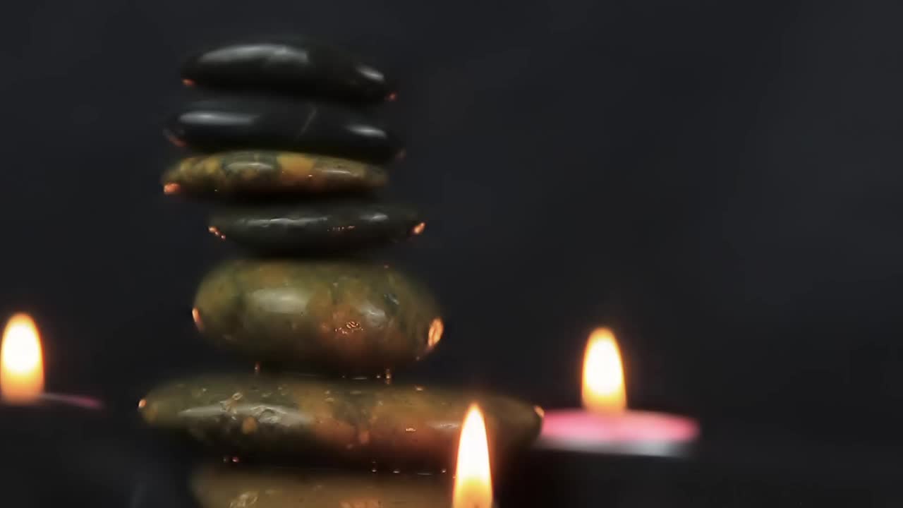 在黑暗中燃烧着蜡烛，在黑暗背景的石头旁滚动着白毛巾视频下载