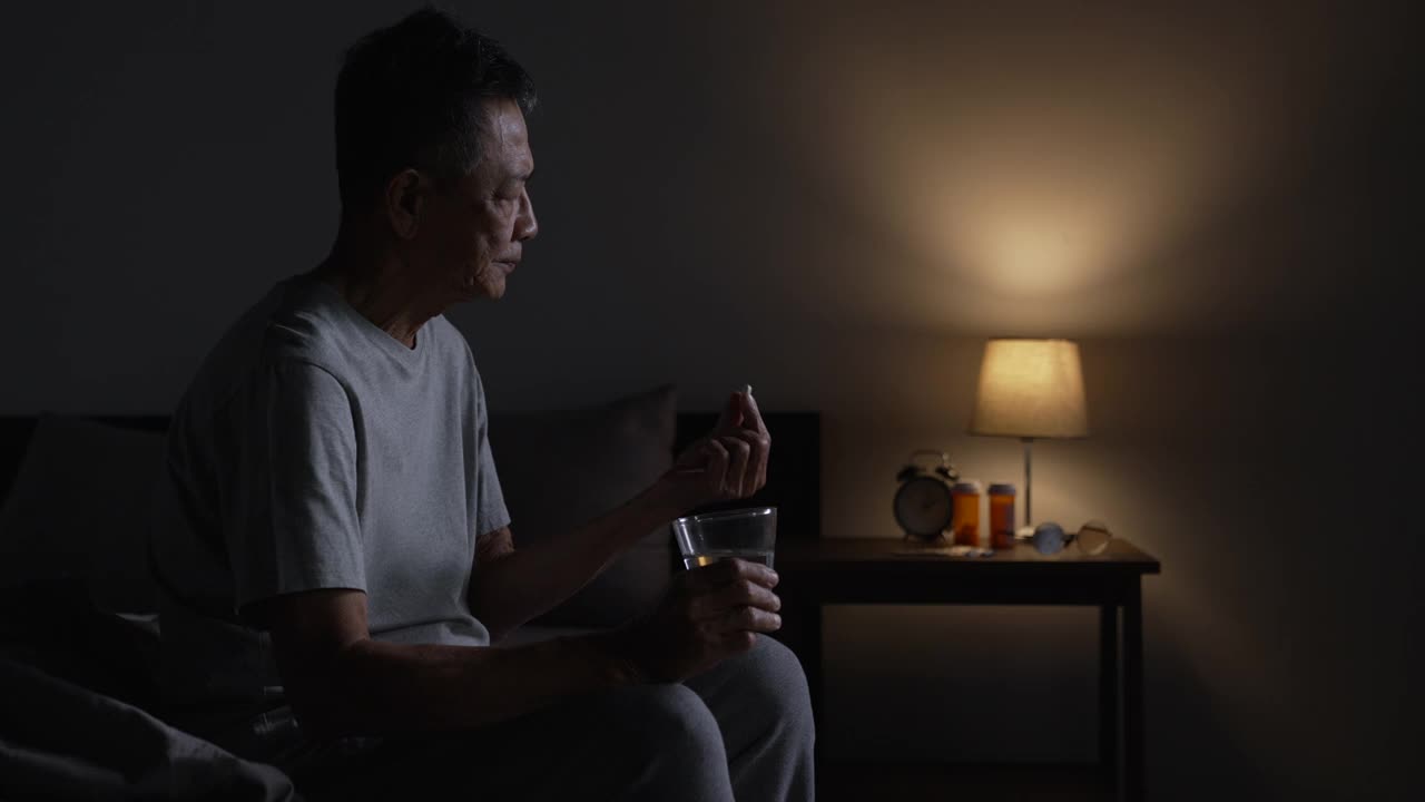 抑郁的亚洲老年男子因失眠而无法入睡。年长的亚洲男子服用安眠药。视频素材