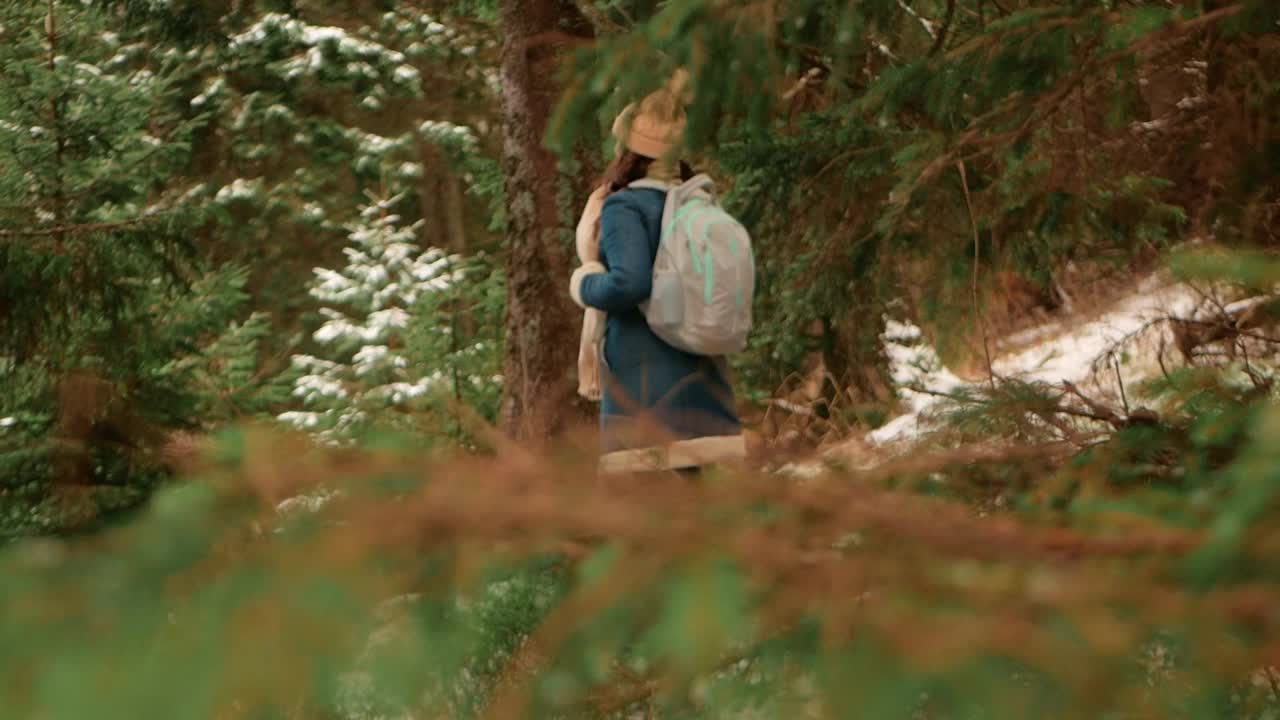 女人走在冬天的森林里，在山上，慢镜头。视频下载