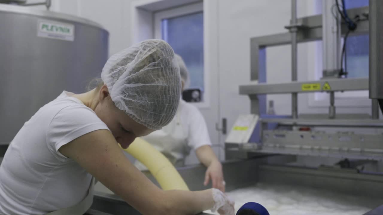 奶牛场工人收集热奶酪凝乳形成一个大锅，用手搅拌它-奶牛场视频下载