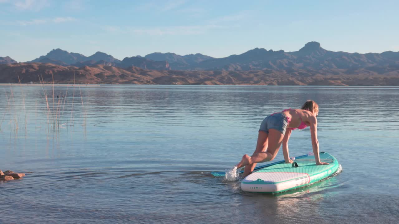 年轻女子站起来划桨(SUP)在宁静的湖视频下载