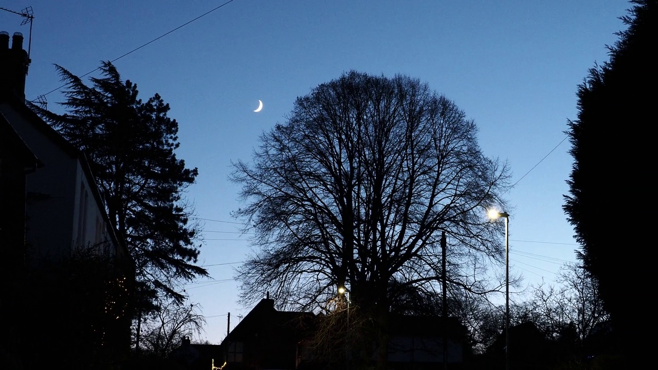 英国利斯特郡拉夫堡附近的伍德豪斯屋檐下，一轮新月落在房屋上空。视频下载