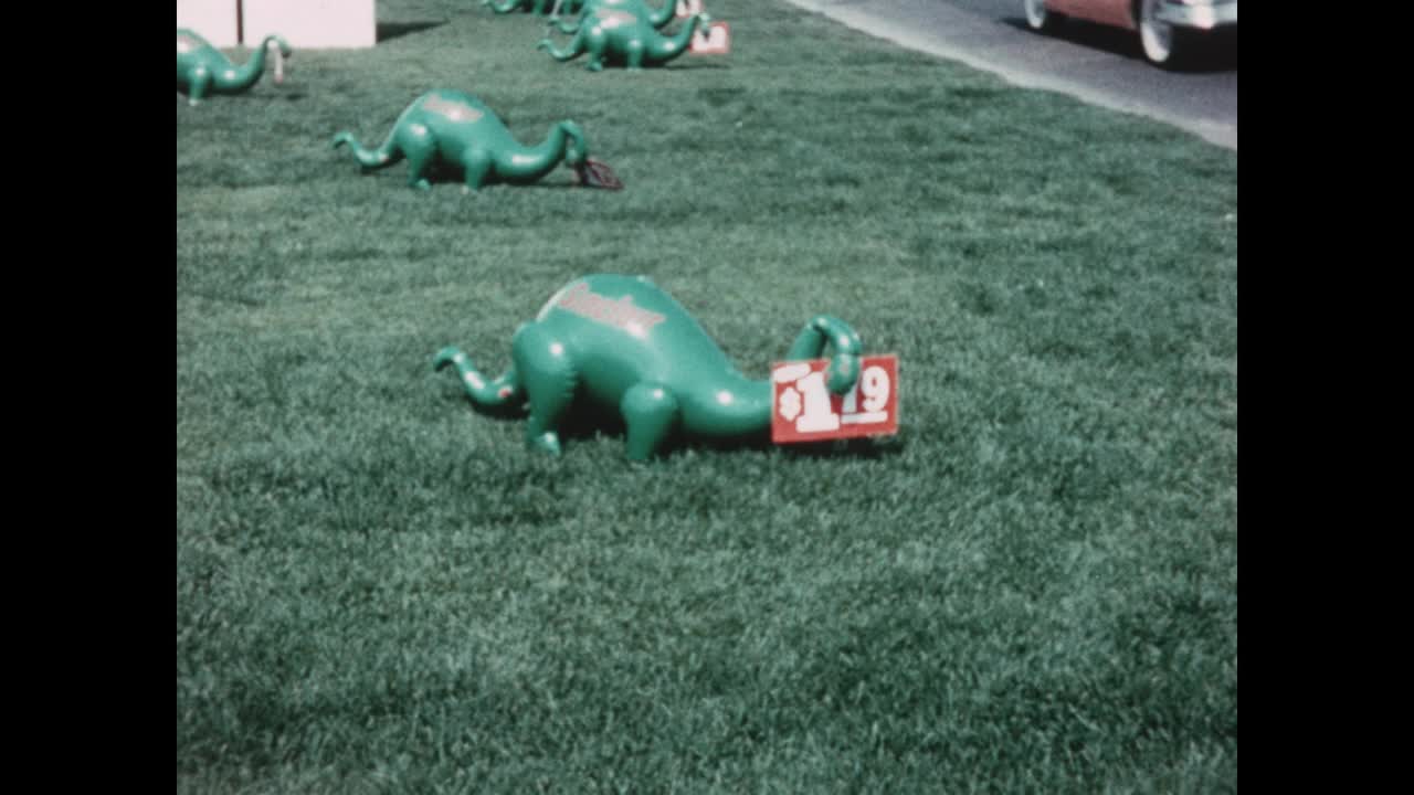 1958年，美国密歇根州迪尔伯恩，一个男孩在辛克莱石油加油站的盛大开业仪式上玩一个充气的绿色恐龙视频下载