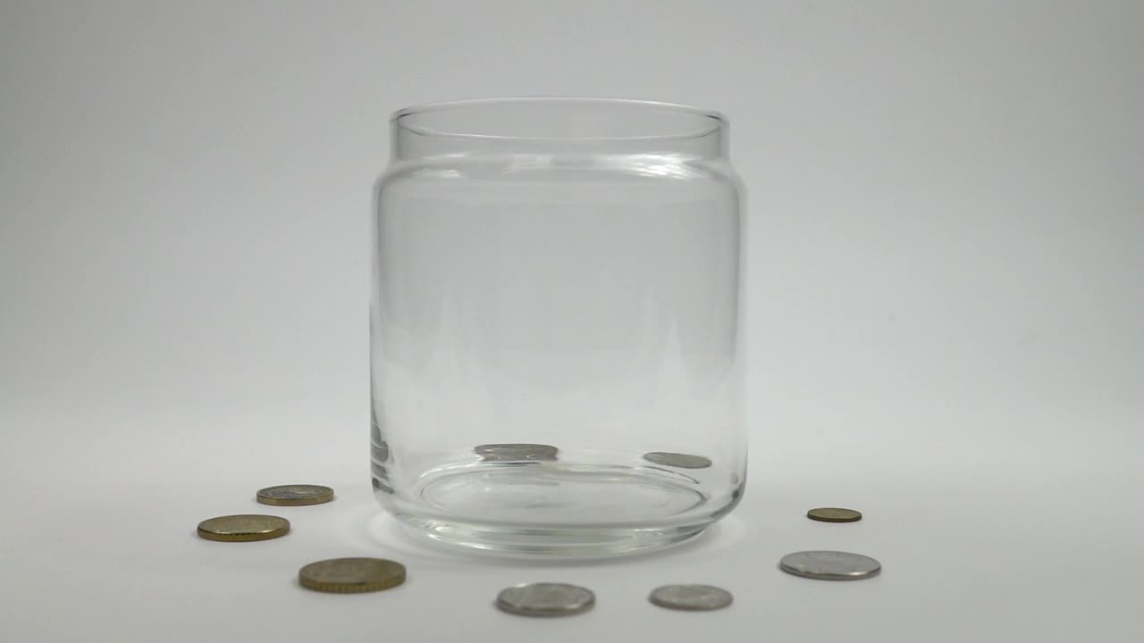 收集不同的硬币落入玻璃罐中，慢动作视频下载