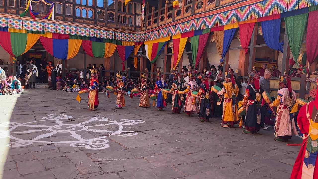 在寺庙广场上，不丹人民穿着五彩缤纷的仪式服装，向巨大的挂毯赠送礼物。视频下载