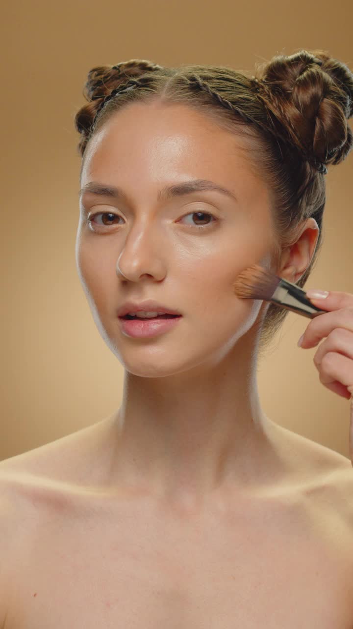 女人在脸上涂了古铜色化妆品。视频素材
