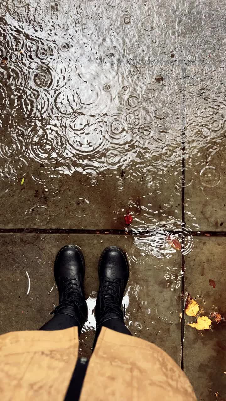 女人脚上穿着皮靴站在雨中的水坑前视频下载