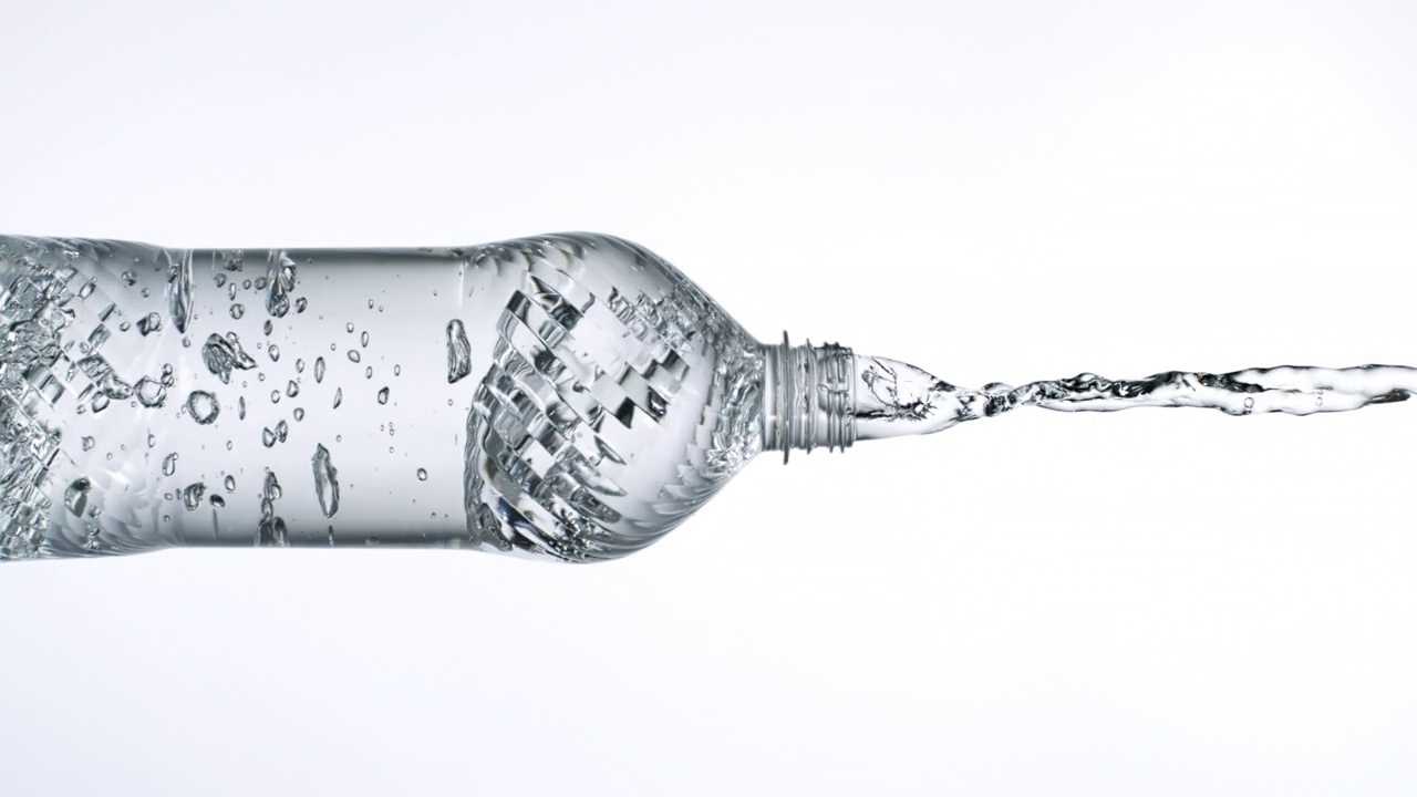 近距离和超级慢动作的倾倒和飞溅水晶清澈的水从一个透明的水瓶喷口在白色背景在多功能水平和垂直格式视频素材