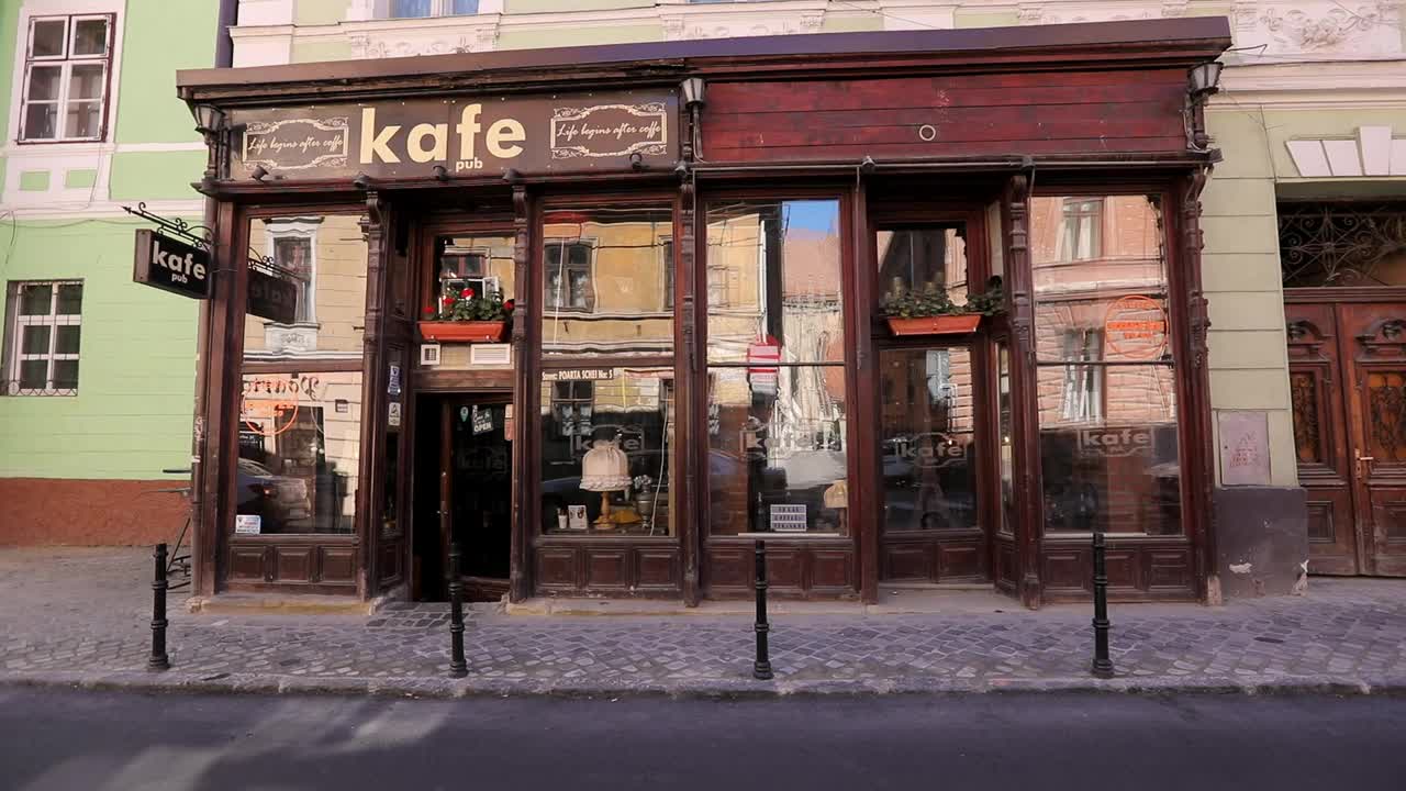 一个人经过人行道上的一家复古咖啡馆，环顾四周，一辆车开过视频下载