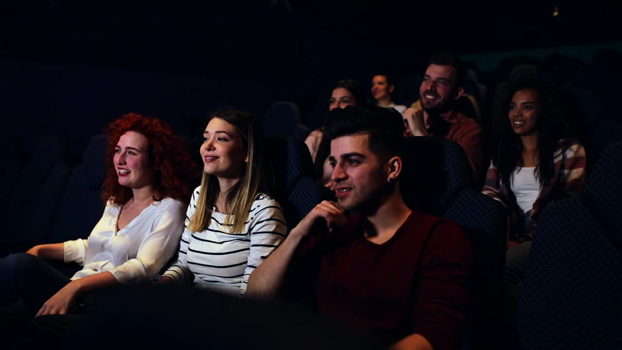 一群兴高采烈的人在电影院边看电影边笑。视频下载